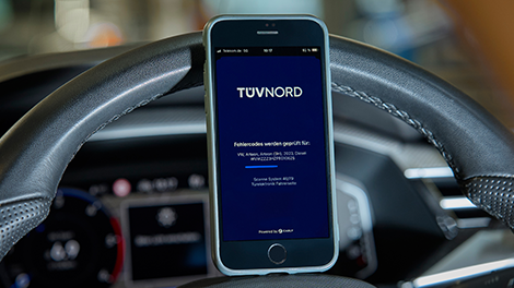 TÜV NORD Guardian Fehlerspeicheranalyse Fehleranalyse auf Smartphone. Das Handy steht auf dem Lenkrad eines Autos.